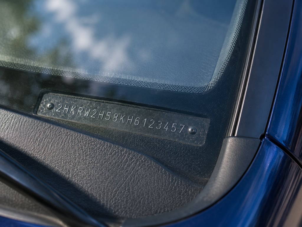 Primer plano de la placa del VIN en la base del parabrisas con los 17 caracteres visibles